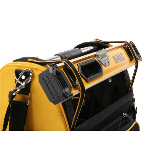 Close-up of a DEWALT yellow and black tool bag with a level tool secured on top using integrated straps.