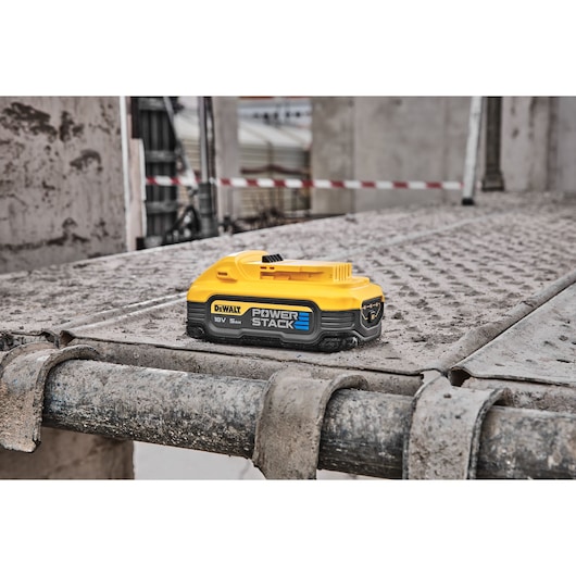 DEWALT Power Stack battery sits on a dusty metal surface at a construction site.