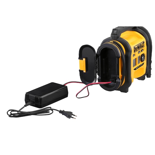 DEWALT portable air compressor model DCC018N in yellow and black. The device is shown with its side compartment open, revealing internal wiring connected to a black power adapter with a European plug.