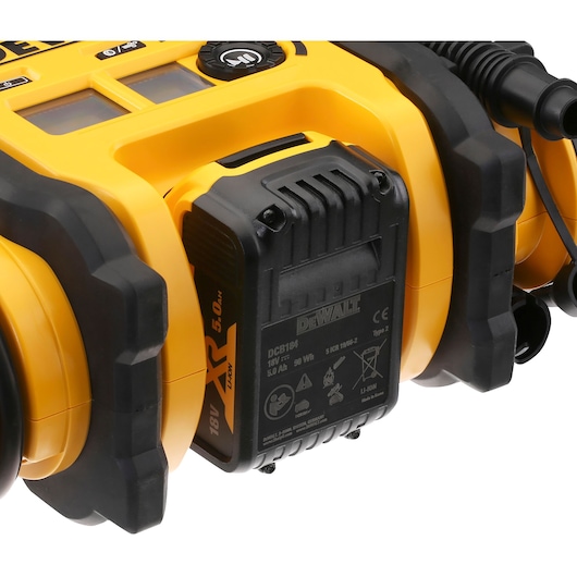 Close-up of a DEWALT DCC018N portable air compressor, showing its yellow and black housing, battery compartment, and control panel with display screens and a knob.