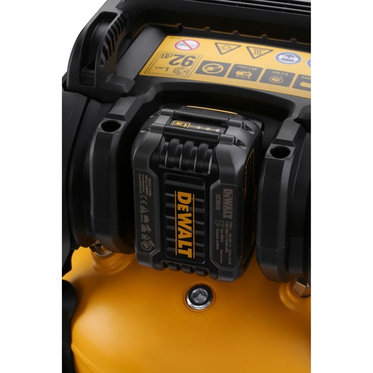 Close-up of a DEWALT battery attached to a yellow device with visible warning labels.