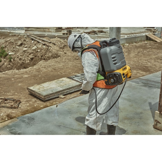 Worker uses DEWALT DCCS1100N-XJ, DCCS1100N sprayer at construction site. Photography product category.