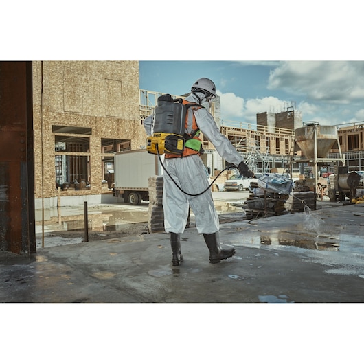 DEWALT DCCS1100N-XJ, DCCS1100N in use on construction site. Worker sprays surface, wearing full protective gear.