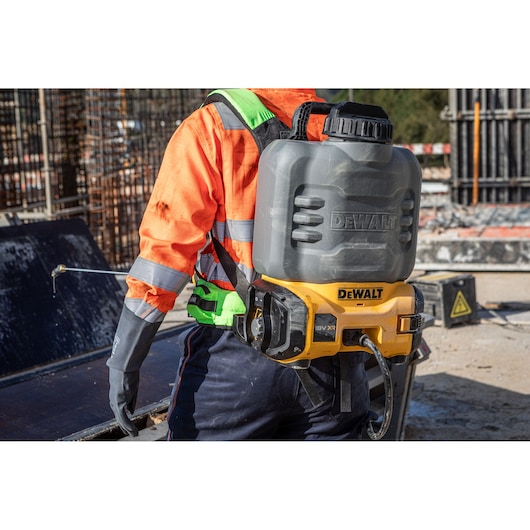 DEWALT sprayer worn on back. SKUs: DCCS1100N-XJ, DCCS1100N. Used outdoors, worker in hi-vis gear.
