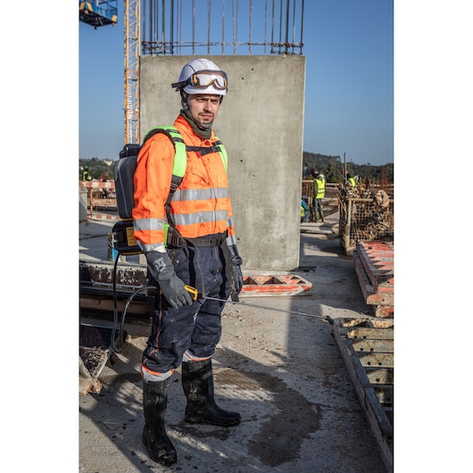 Worker with DEWALT DCCS1100N-XJ, DCCS1100N sprayer gear at site, photography category.