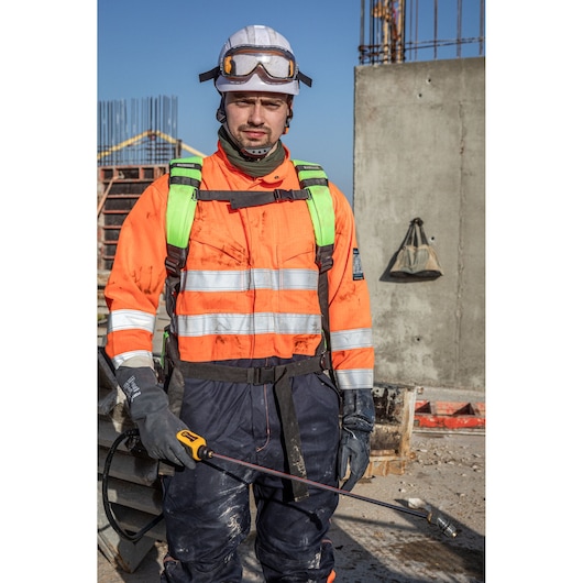 Worker in DEWALT gear at site, holding device, DCCS1100N-XJ, DCCS1100N. Photography category.