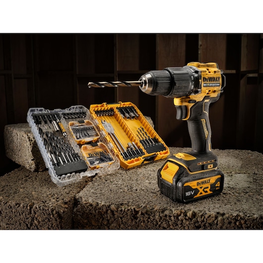 DEWALT cordless drill with accessories and drill bit sets, placed on concrete blocks in a workshop setting.