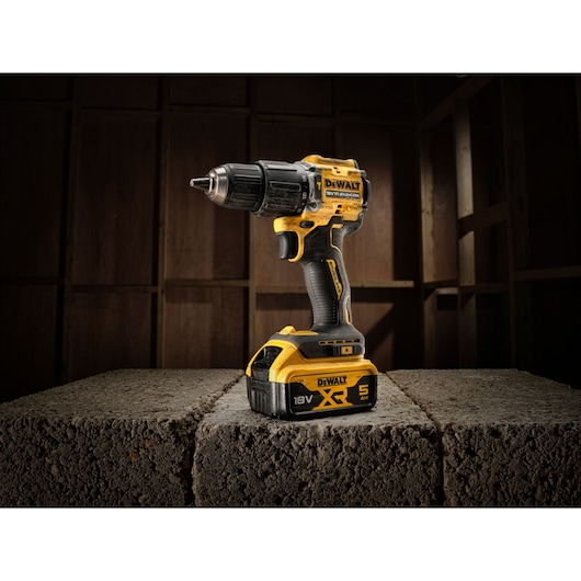 DEWALT cordless drill with 18V XR battery stands on concrete blocks in a workshop.