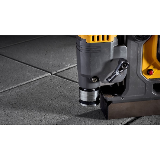 Close-up of a DEWALT tool pressing onto concrete tiles, showing its metallic base and adjustment lever.