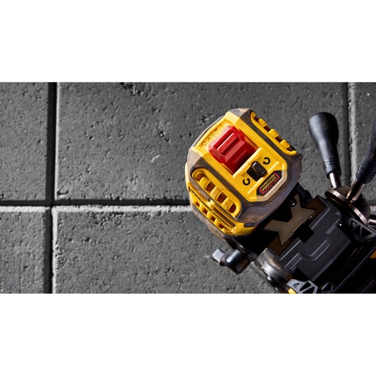 Close-up of a DEWALT tool with yellow casing and controls, placed on a textured gray tile floor.