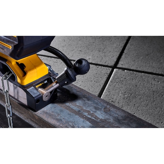 Close-up of a DEWALT tool attached by chain to a metal beam, shown on a textured concrete floor.