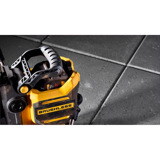Close-up of a DEWALT brushless power tool with a black handle, placed on large gray concrete tiles.