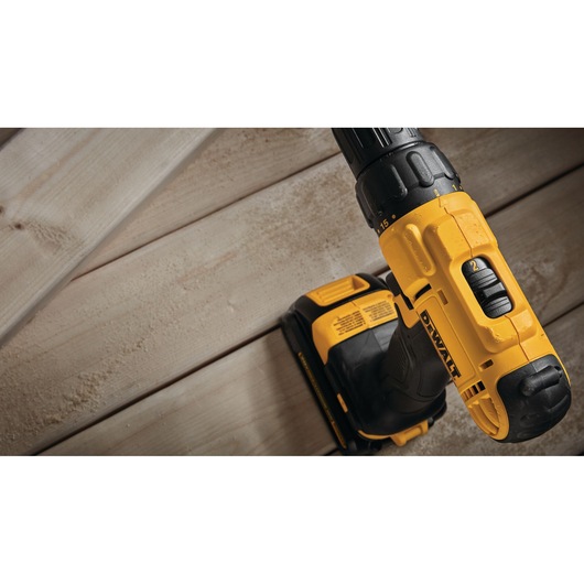Close-up image of a yellow and black DEWALT cordless drill resting on light wooden boards.