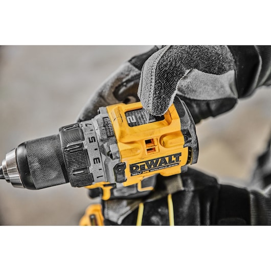 Close-up of a gloved hand adjusting a DEWALT cordless power drill, model DCD800E2T, with a yellow and black design.