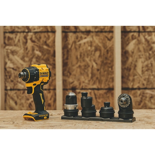 A DEWALT cordless drill with multiple interchangeable heads is displayed on a wooden surface in a workshop setting.