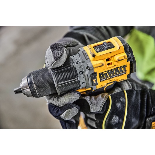 Close-up of a gloved hand holding a DEWALT 18V XR brushless cordless drill.