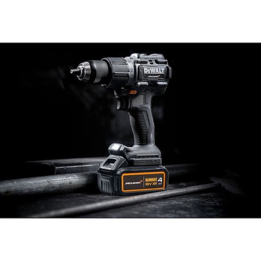 DEWALT cordless drill with 18V XR 4Ah McLaren battery, displayed in a dark industrial setting.