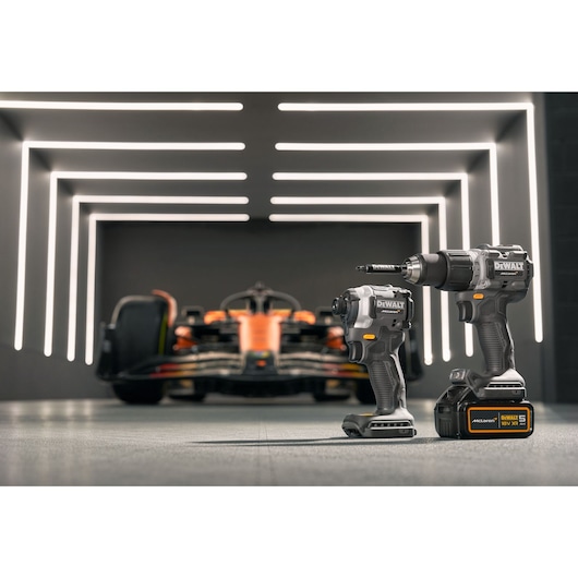 Two DEWALT power tools in focus, race car blurred in background, modern lighting design.