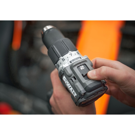 Hand adjusting DEWALT cordless drill settings, close-up of tool and speed selector.