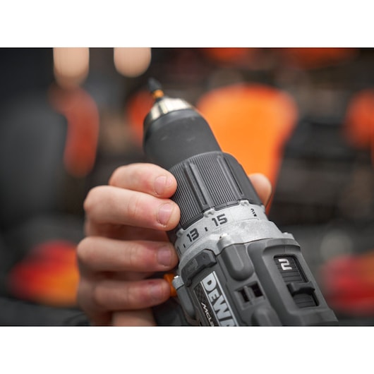 Hand holding a DEWALT cordless power drill, showing adjustable settings and grip.