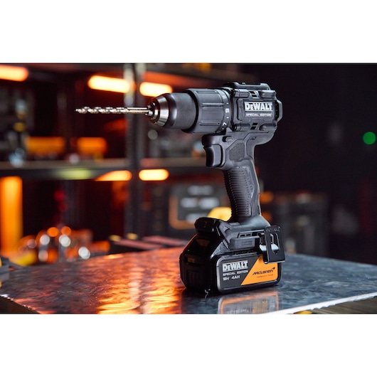 Cordless DEWALT drill with battery, placed on a metallic surface, workshop background, McLaren Special Edition.