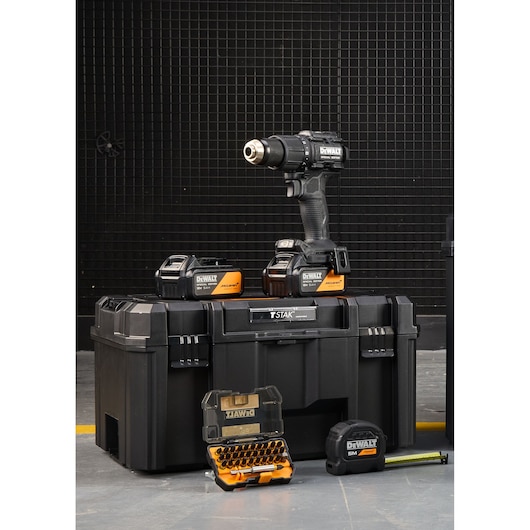 DEWALT cordless drill kit with batteries, toolbox, bit set, and tape measure on a workshop floor.