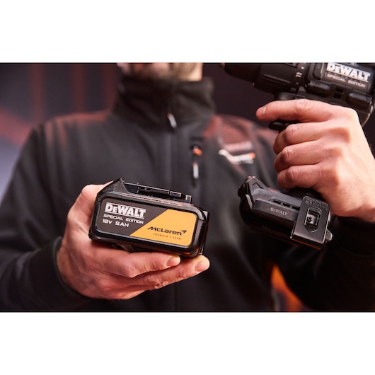 Man holds a DEWALT special edition 18V 5Ah McLaren battery and DEWALT power tool in hands, focus on products.