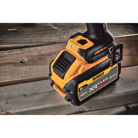 Close-up of a DEWALT XR FlexVolt 18V/54V 6Ah battery attached to a power tool, placed on wooden boards.