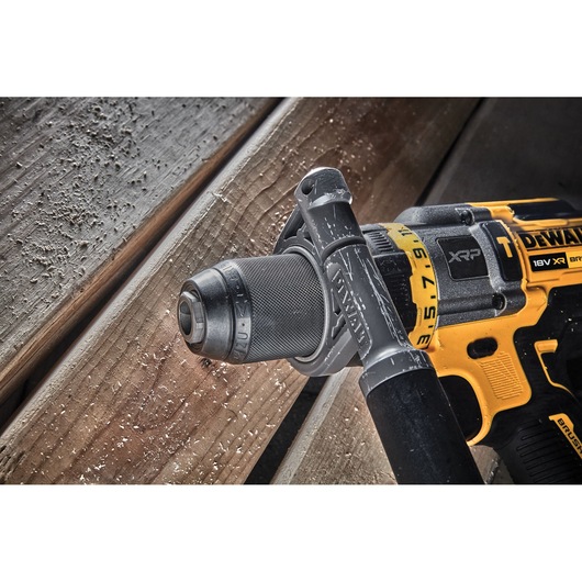 Close-up view of a DEWALT 18V XR cordless drill in use on wooden planks, with wood shavings visible.