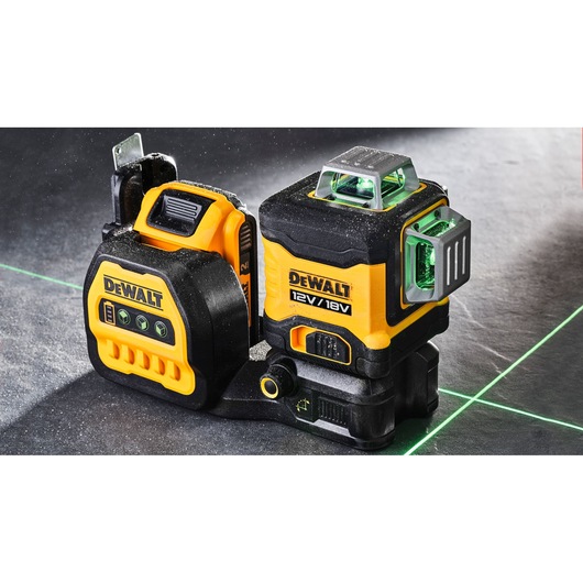 DEWALT 12V/18V green line laser level device set shown on a surface, emitting bright green laser lines for precise alignment.