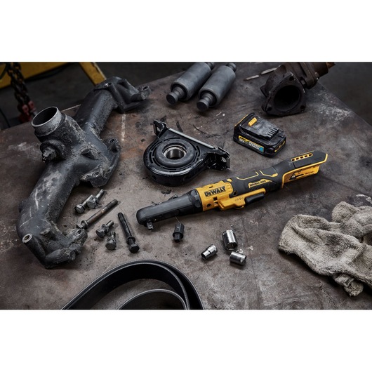 DEWALT cordless ratchet tool on a workbench with automotive parts and accessories.