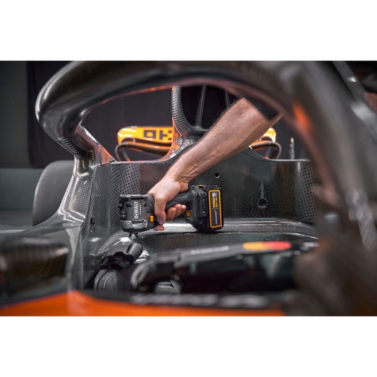 A DEWALT power tool being used inside a race car cockpit, focusing on mechanical work.