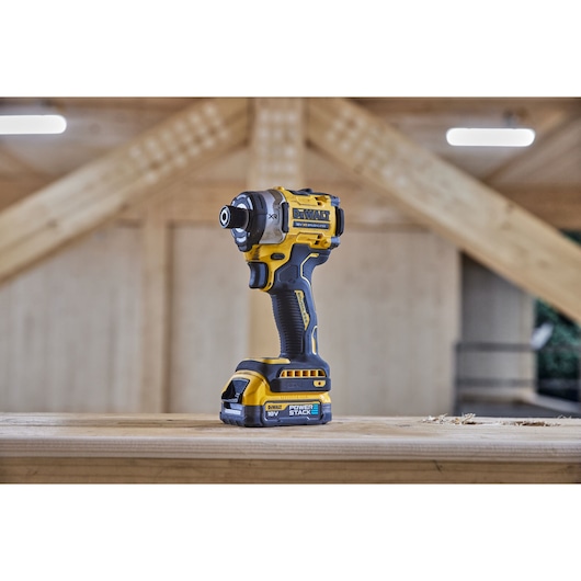 DEWALT cordless impact driver on a wooden surface in a workshop setting.