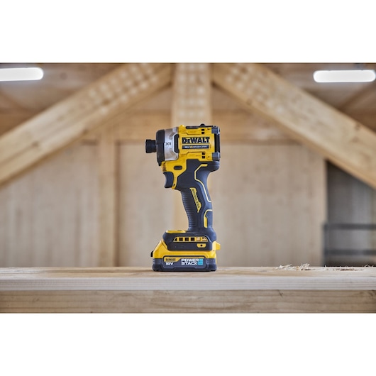 DEWALT DCF860E2T 18V cordless impact driver standing on a wooden surface in a workshop setting.