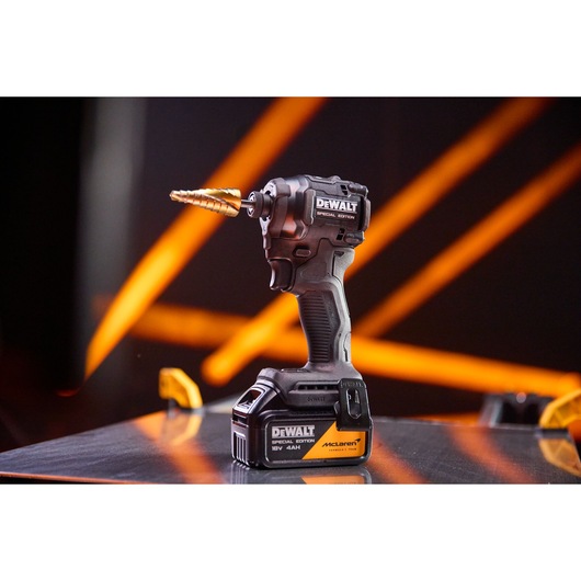 DEWALT cordless drill with special edition label and step drill bit, displayed on a reflective surface with orange lights.
