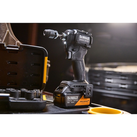 DEWALT cordless impact wrench with case and accessories shown on a workbench in a workshop setting.
