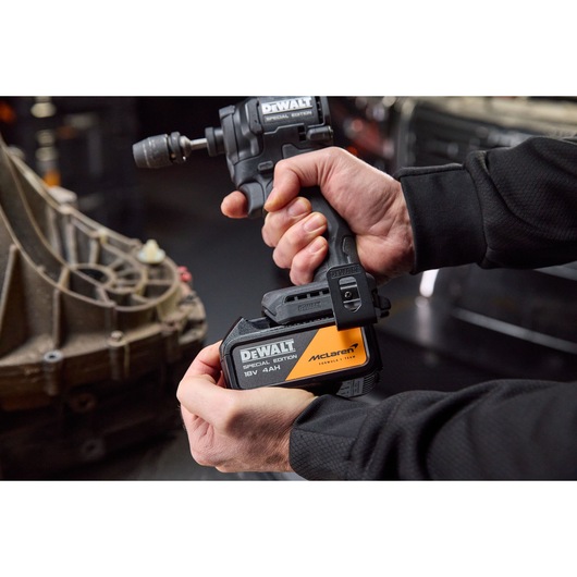 A person uses a DEWALT Special Edition 18V cordless drill with McLaren branding in a workshop setting.