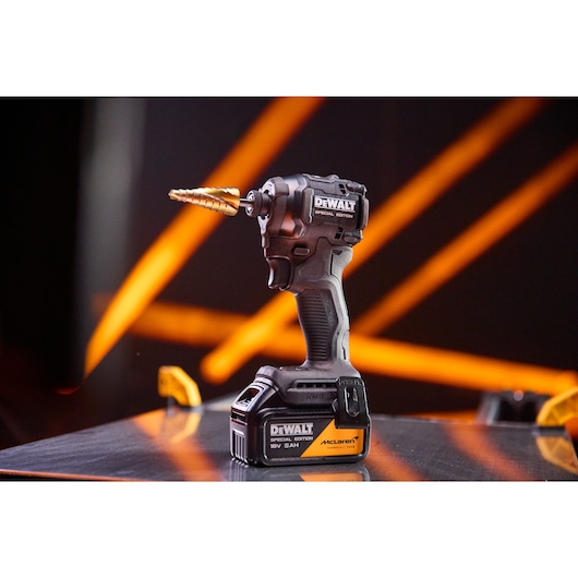 DEWALT cordless drill with step bit, special edition, on display with orange streaks in background.