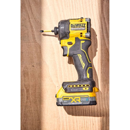 Yellow and black DEWALT XR 18V cordless impact driver on a wooden background.