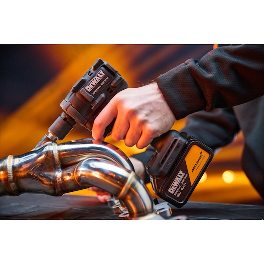 DEWALT tool in use, shown with SKUs DCF92MP2T-QW and DCF92MP2T. Industrial setting with metal pipes.