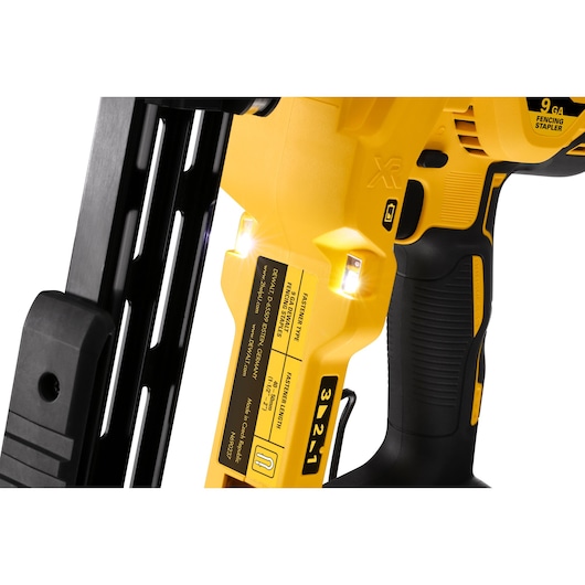 Close-up view of a DEWALT DCFS950P2 9-gauge fencing stapler, showing its yellow body, black handle, and LED lights near the staple release area.