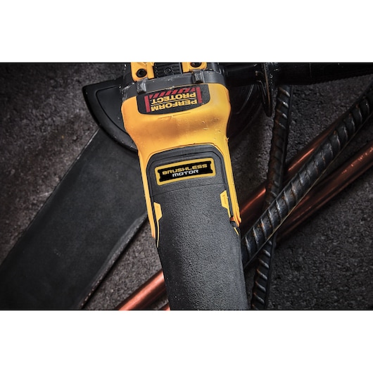 Close-up of a DEWALT brushless motor tool handle on a rough surface with metal rods.