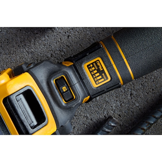 Close-up of DEWALT tool handle showing RPM settings dial and textured grip against a concrete surface.