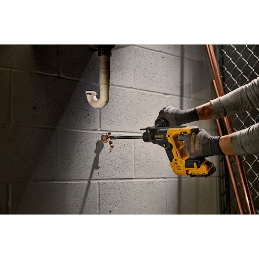 DEWALT tool in use drilling pipe. SKUs: DCH072NT, DCH072N, DCH072N-XJ. Product category: Photography.