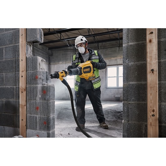 Worker uses DEWALT DCH911NK rotary hammer to drill a concrete wall at a construction site.