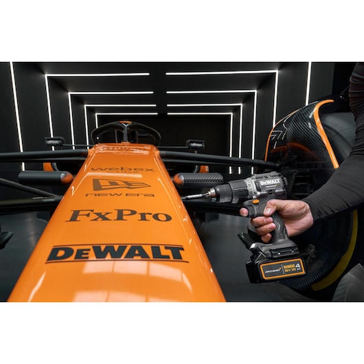 A close-up view of an orange Formula 1 race car with visible sponsor logos, including DEWALT, FxPro, New Era, and Webex