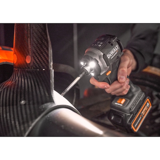 A DEWALT cordless power tool is used to drive a screw into a carbon fiber component in a workshop setting.