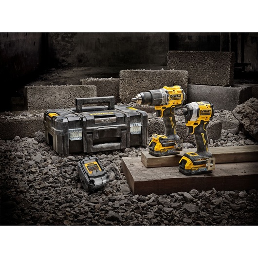 DEWALT tool set with two drills, charger, and toolbox on a rocky construction site.