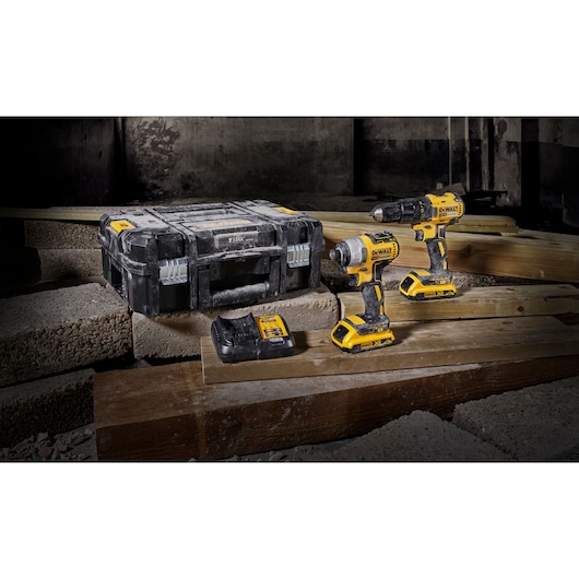 DEWALT cordless power tool kit displayed on wooden planks, including a black and yellow drill driver, impact driver, battery