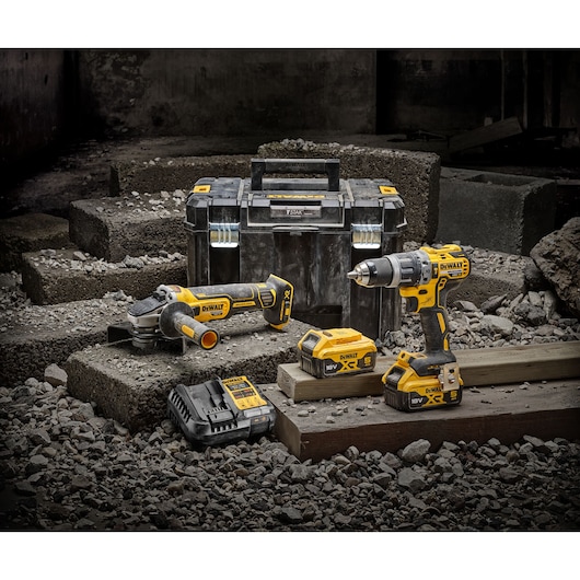 DEWALT tool kit with drill, grinder, charger, batteries, and case displayed on concrete blocks.